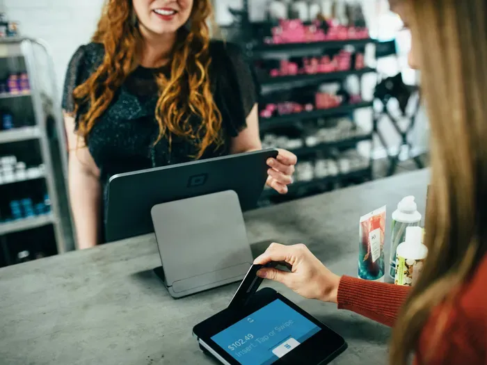 Smiling cashier and customer completing a purchase with credit card using modern point-of-sale system